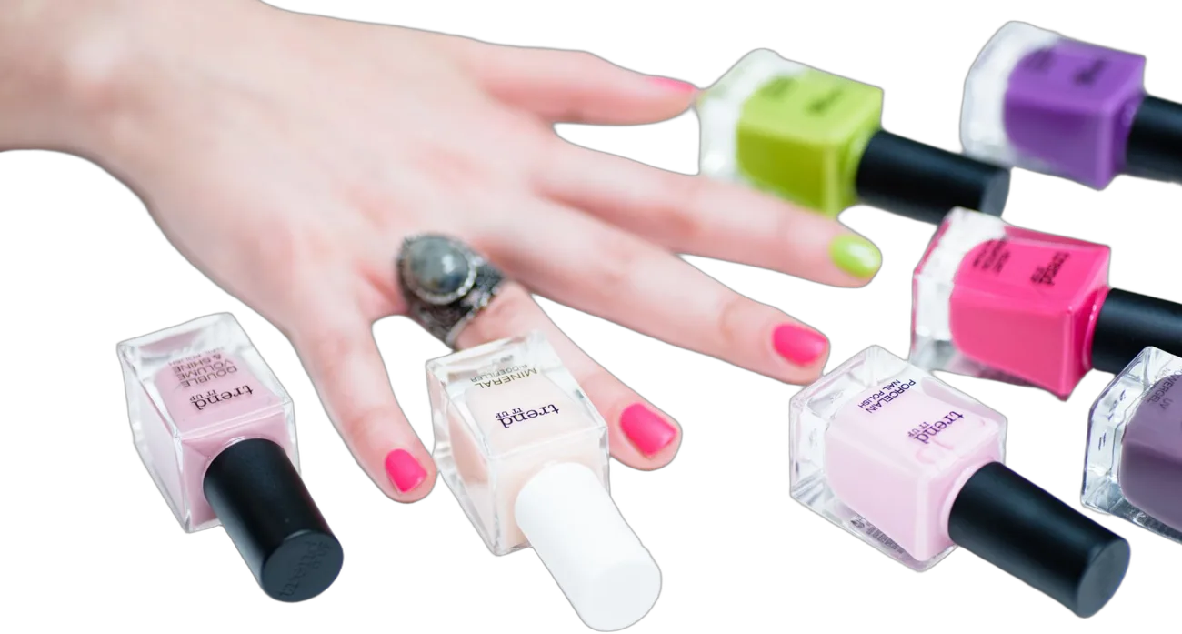 Mão com unhas pink entre frascos de esmalte coloridos